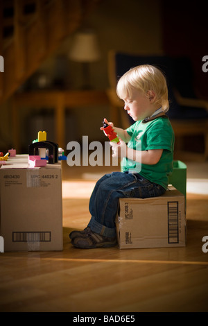 Bambino gioca con giocattoli su scatole di cartone Foto Stock