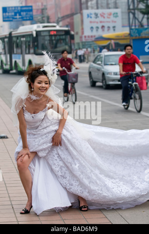 Sposa abito da sposa colpisce glamour posa per il fotografo sul mall pedonale Wangfujing Street, Pechino, Cina Foto Stock