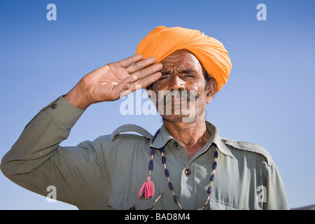 Uomo che indossa un colorato turbante di zafferano e salutando a Osian Camel Camp, Osian, Rajasthan, India Foto Stock