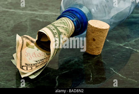 Bottiglia con un rotolo di denaro proveniente dall'alto accanto a un tappo di sughero Foto Stock