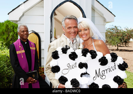 Ritratto di sposi novelli e sacerdote di fronte cappella, Niagara Falls Ontario, Canada Foto Stock