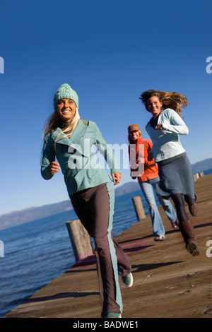 Amici in esecuzione sul Dock, Lake Tahoe, CALIFORNIA, STATI UNITI D'AMERICA Foto Stock