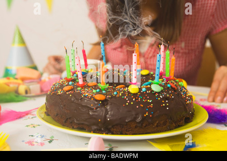 Donna soffiando le candeline sulla torta di compleanno Foto Stock