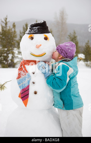Ragazza baciare pupazzo di neve, vicino a Frisco, Summit County, Colorado, STATI UNITI D'AMERICA Foto Stock