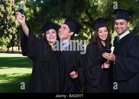 Laureati con i telefoni cellulari Foto Stock