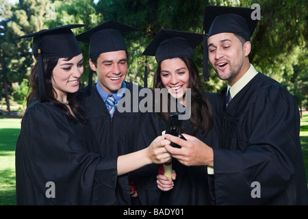 Laureati con i telefoni cellulari Foto Stock