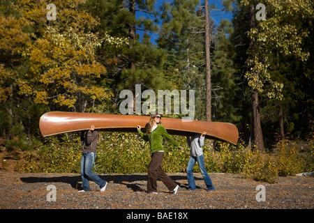 Tre donne che portano la canoa nella foresta Foto Stock