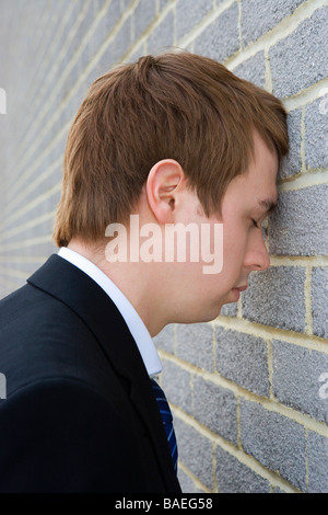 Imprenditore con la testa contro un muro di mattoni Foto Stock