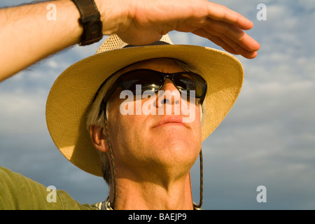 Messico Todos Santos di mezza età maschio caucasico indossando cappello di paglia e occhiali da sole guardare nella distanza proteggere gli occhi dal sole a mano Foto Stock
