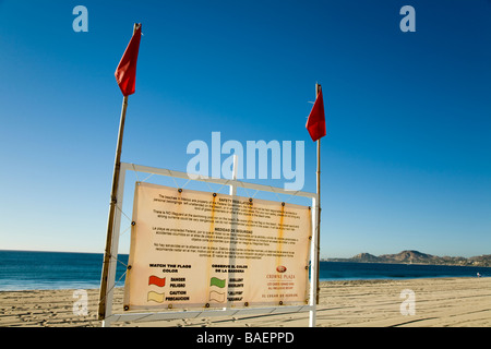 Messico San Jose del Cabo bandiere rosse presso la spiaggia di avvertimento di condizioni pericolose sign in inglese e in spagnolo per spiegare le bandiere Foto Stock