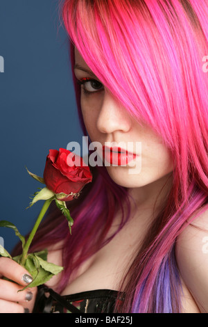 Ritratto di un 18 anni ragazza gotica con luminosi capelli rosa tenendo una rosa Foto Stock