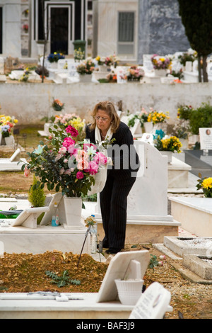 ESTORIL PORTOGALLO donna nel cimitero di rose dispone sulla tomba di un membro della famiglia Foto Stock