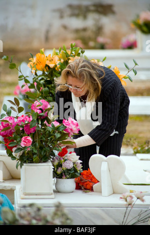 ESTORIL PORTOGALLO donna nel cimitero di rose dispone sulla tomba di un membro della famiglia Foto Stock