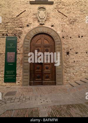 Un scolpito porta in legno che si trova su un'antica strada acciottolata nella città di Gubbio, Italia. Foto Stock