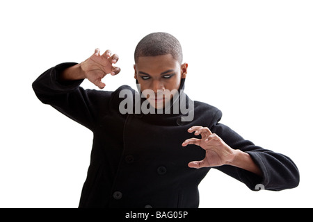 L'uomo africano con bianco smokey eyes una forte espressione e mantello nero isolato Foto Stock
