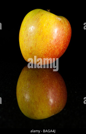 La Braeburn apple sul riflesso in un pezzo di lucido granito nero Foto Stock