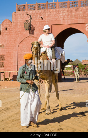 Driver del cammello e il turista a cavallo su un cammello, a Osian Camel Camp, Osian, Rajasthan, India Foto Stock