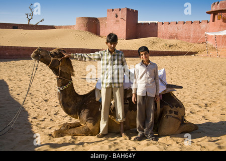 Cammello e due giovani ragazzi a Osian Camel Camp, Osian, Rajasthan, India Foto Stock