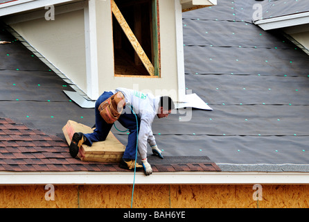 Un uomo ispanico si applica le assicelle per il tetto di una nuova casa in Oklahoma City, Oklahoma, Stati Uniti d'America. Foto Stock