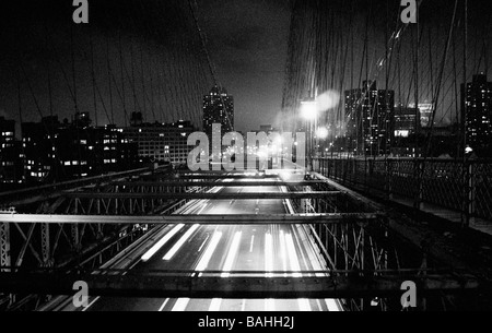I sentieri dei fari del traffico sotto le travi del ponte di Brooklyn a New York City. Foto Stock