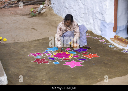 Donna indiana mettendo i bastoncini di incenso in un'offerta di fiori e di sterco di vacca su un Rangoli design in un Indiano street Foto Stock