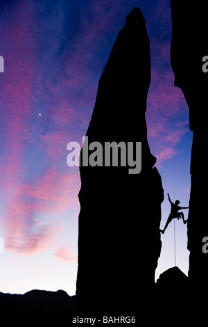 Un scalatore si profila come egli raggiunge attraverso un varco nella roccia nelle montagne della Sierra Nevada in California Foto Stock