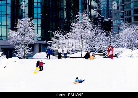 Bambini e genitori di giocare e slittino sulla collina nel centro di neve in 'West End' di Vancouver British Columbia Canada in inverno Foto Stock