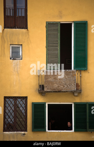 Un giovane seduto a pranzo in una finestra shutterd in Piazza Anfiteatro, Luca, Toscana, Italia Foto Stock
