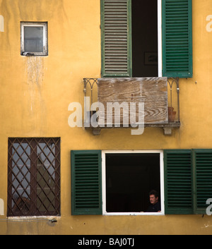 Un giovane seduto a pranzo in una finestra shutterd in Piazza Anfiteatro, Luca, Toscana, Italia Foto Stock