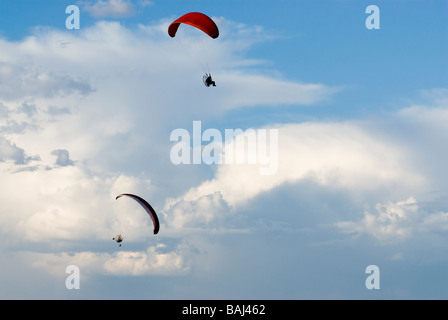 Due piloti di parapendio in volo contro il drammatico nuvole Foto Stock