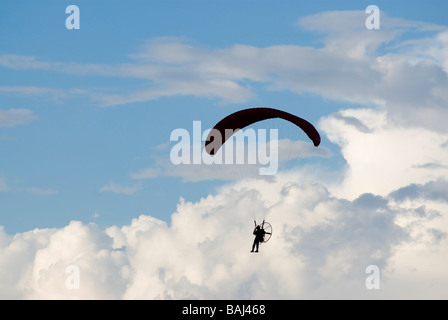 Un powered pilota di parapendio in volo con un cielo nuvoloso in background Foto Stock