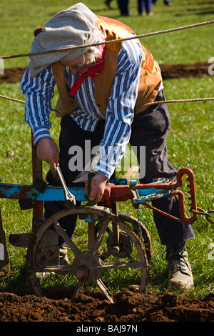 Uomo vestito in costume utilizzando una chiave per risolvere un problema di stile tradizionale aratro, Mauchline, Ayrshire, in Scozia Foto Stock