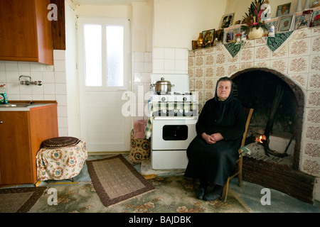 Il vecchio donna nella sua parte anteriore soggiorno in tradizionale costume nero in un villaggio in alta montagna bianca a Creta Foto Stock