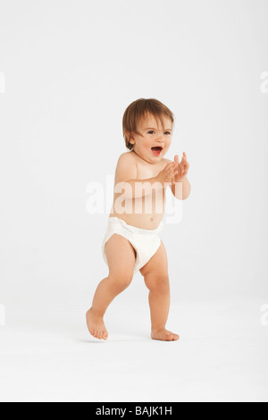 Entusiasta il toddler prendendo i primi passi in bianco studio Foto Stock