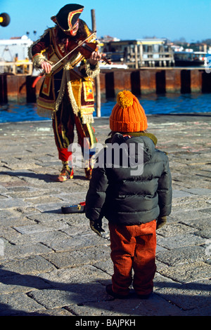 Little Boy guardando il Fiddler in costume medievale sulla banchina a Carnevale a Venezia Italia Foto Stock