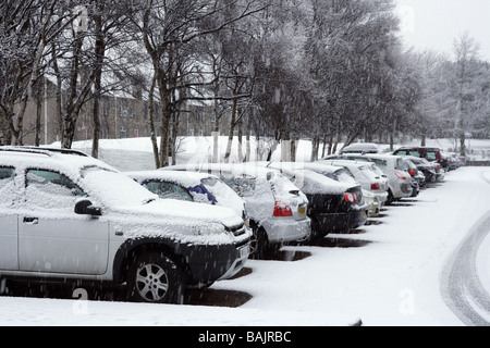 La caduta della neve e la sedimentazione su vetture parcheggiato in un parcheggio. Foto Stock