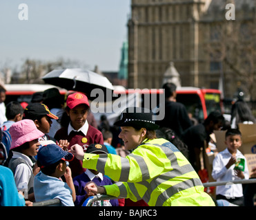 Una donna di polizia metropolitana amichevole che parla con i bambini della scuola tamil ad una protesta a Westminster a Londra. Foto Stock