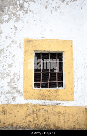 Finestra di piccole dimensioni con barre di ferro in una vecchia cappella. Crato, Alentejo, Portogallo. Foto Stock