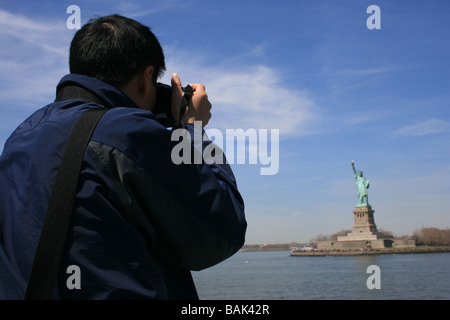 Turistica prendendo le foto della statua della Libertà Foto Stock