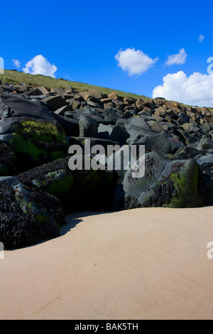 Grande Mare eroso whin rocce di pietra utilizzata come erosione costiera difesa spiaggia Cambois Northumberland Foto Stock