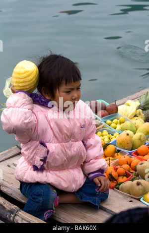 Il vietnamita bambino su una barca per la vendita di frutta nella Baia di Ha Long Vietnam Foto Stock