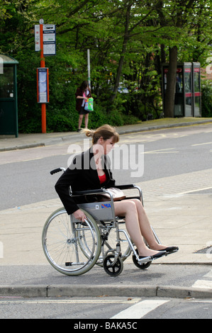 Donna seduta in un auto propel sedia a rotelle viaggiano lungo il marciapiede Foto Stock