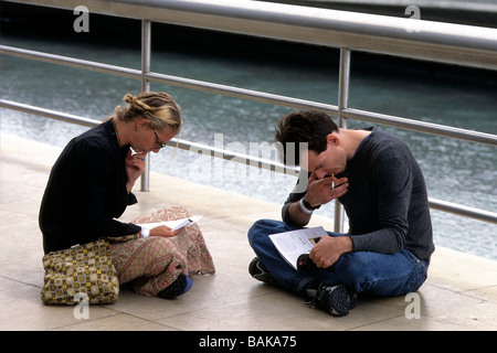 Spagna. I visitatori di prendere del tempo per leggere il Guggenheim Museum Bilbao. Essi sono qui seduti su una delle rampe al di fuori Foto Stock