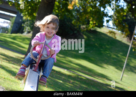 Due e una metà anno vecchia ragazza che si divertono sull'altalena in un parco Foto Stock