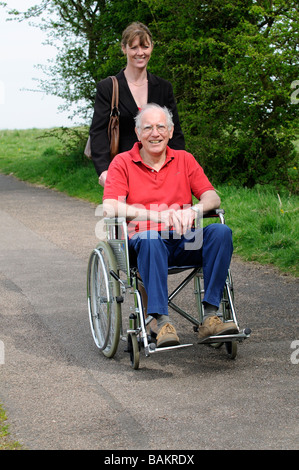 Maschio di sedia a rotelle non valido utente e caregiver femmina spingendo la sedia England Regno Unito Foto Stock