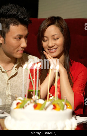 Coppia in cerca felice accanto alla torta di compleanno decorata Foto Stock