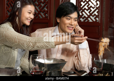 Paio di mangiare in un ristorante, uomo parlando al cellulare Foto Stock