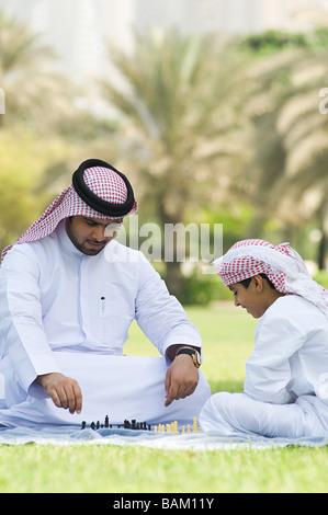 Un padre e figlio giocare a scacchi in un parco Foto Stock