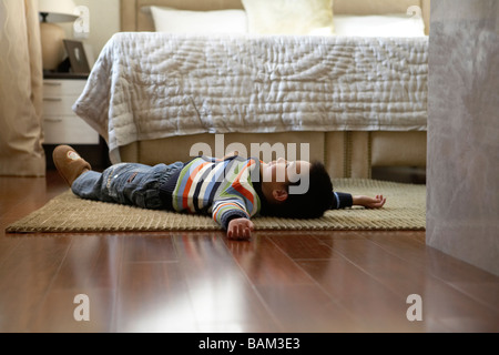 Giovane ragazzo disteso sul pavimento Foto Stock