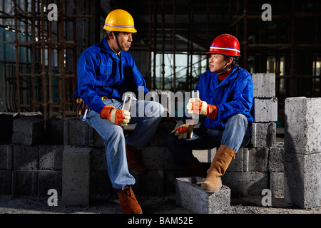 Gli uomini in cantiere Indossare copricapi rigidi Foto Stock